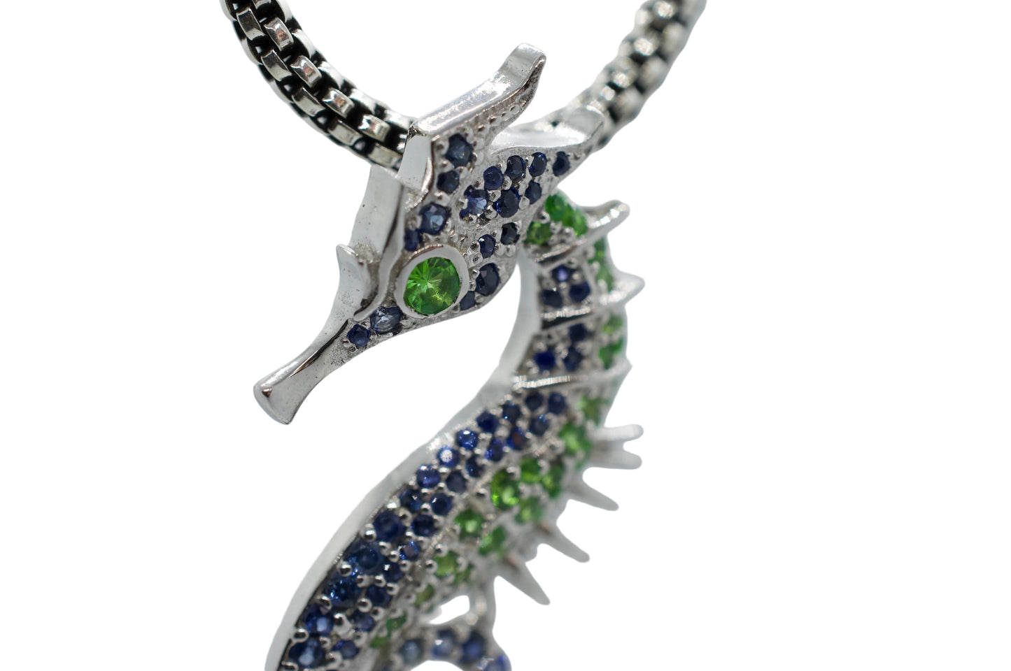 Silver seahorse pendant with blue and green gemstones on a light gray background