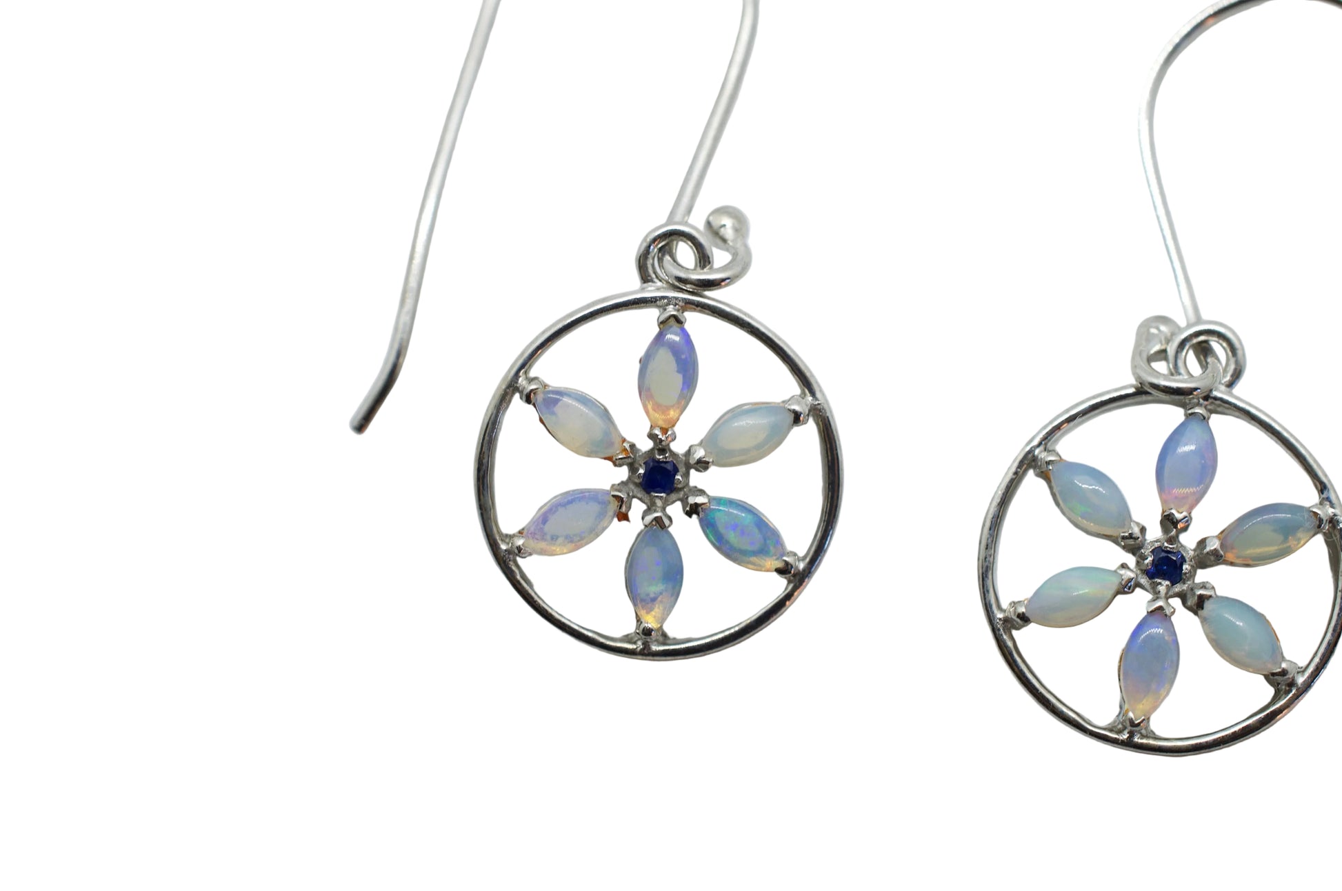 Silver earrings with circular designs and opal-like stones on a light gray background