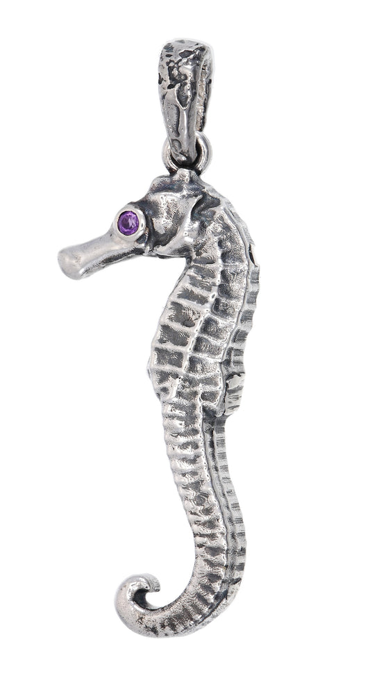 Silver seahorse pendant with a purple gemstone on a white background