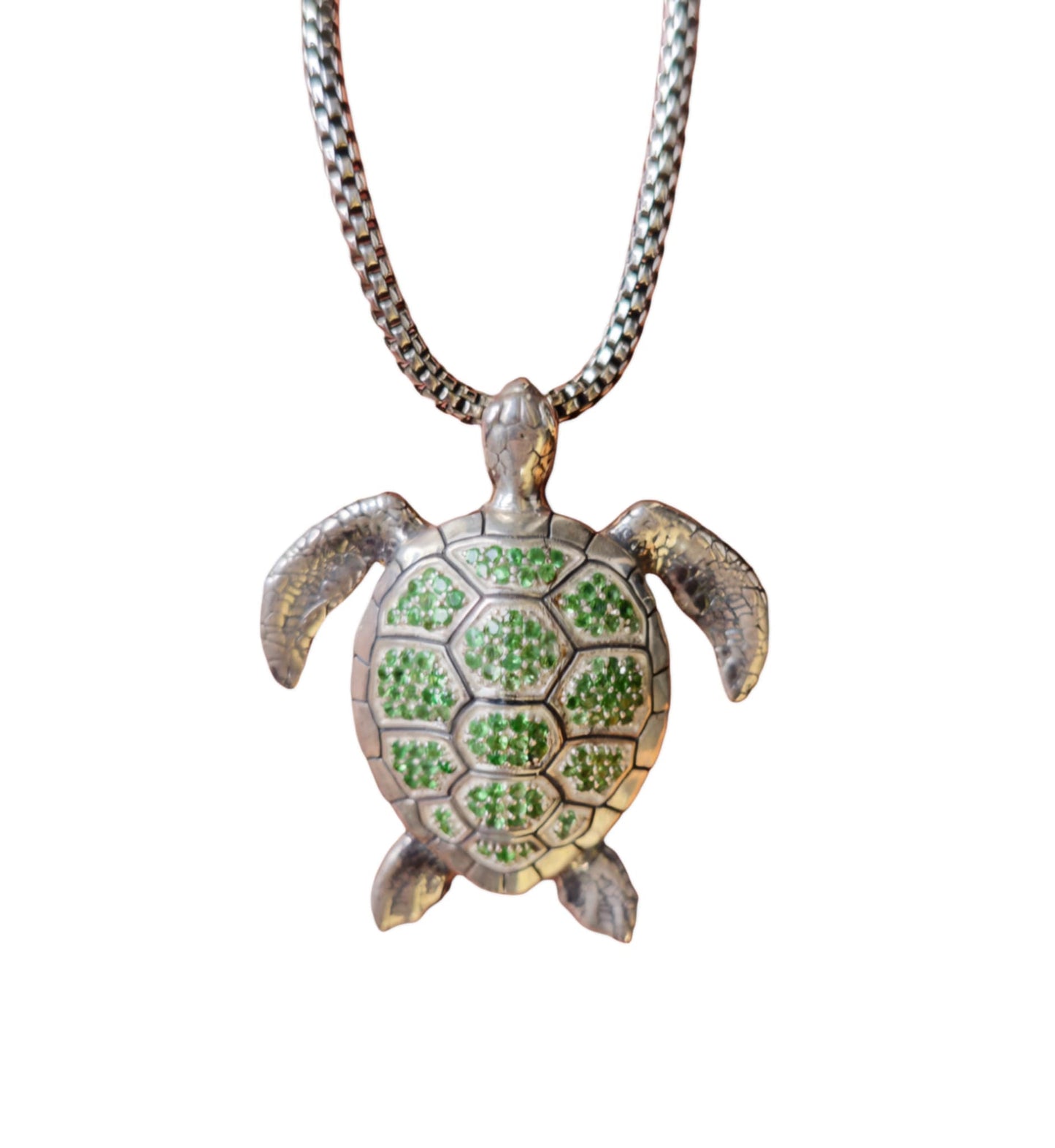 A sterling silver necklace featuring a pendant in the shape of a green sea turtle with tsavorite gemstones.